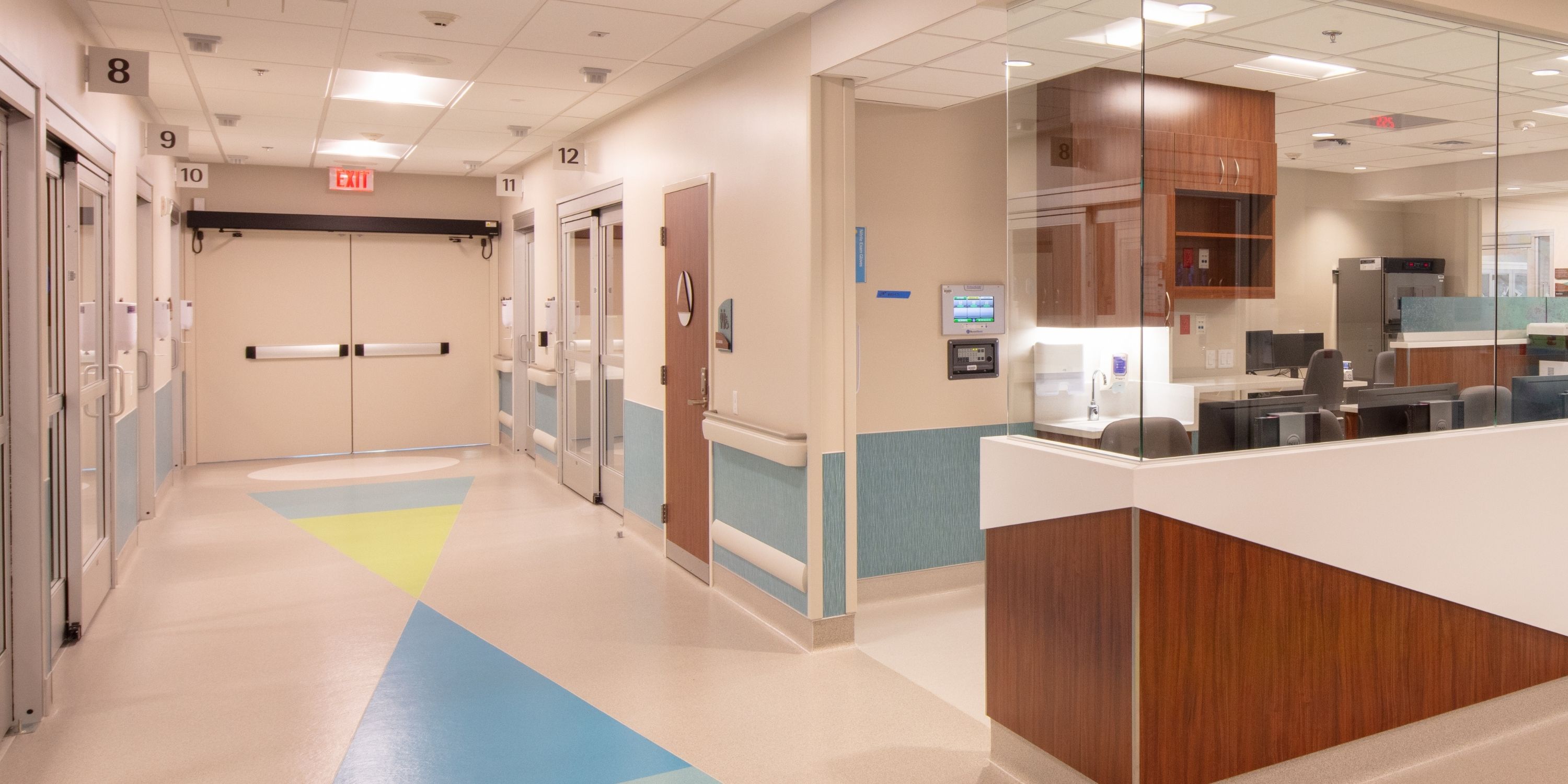 A hospital hallway featuring a reception desk and a service counter, with bright lighting and clean, neutral-colored walls.