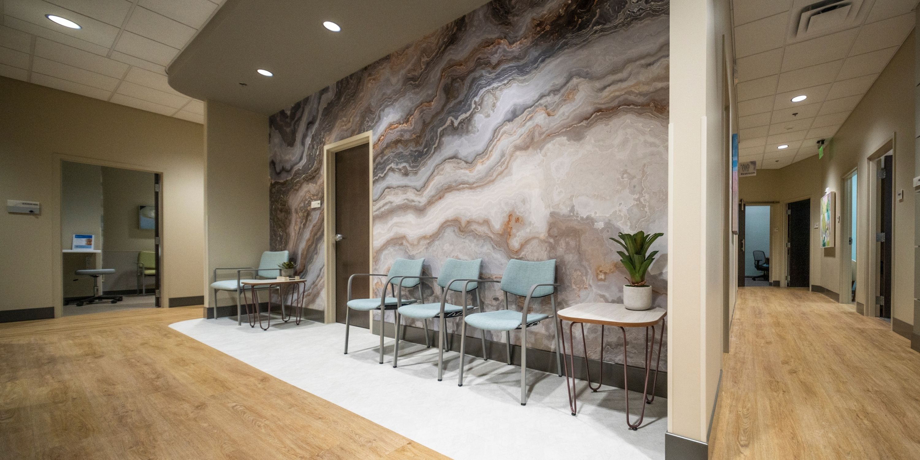 Hospital lobby scene featuring individuals walking, sitting, and interacting near reception and waiting areas.