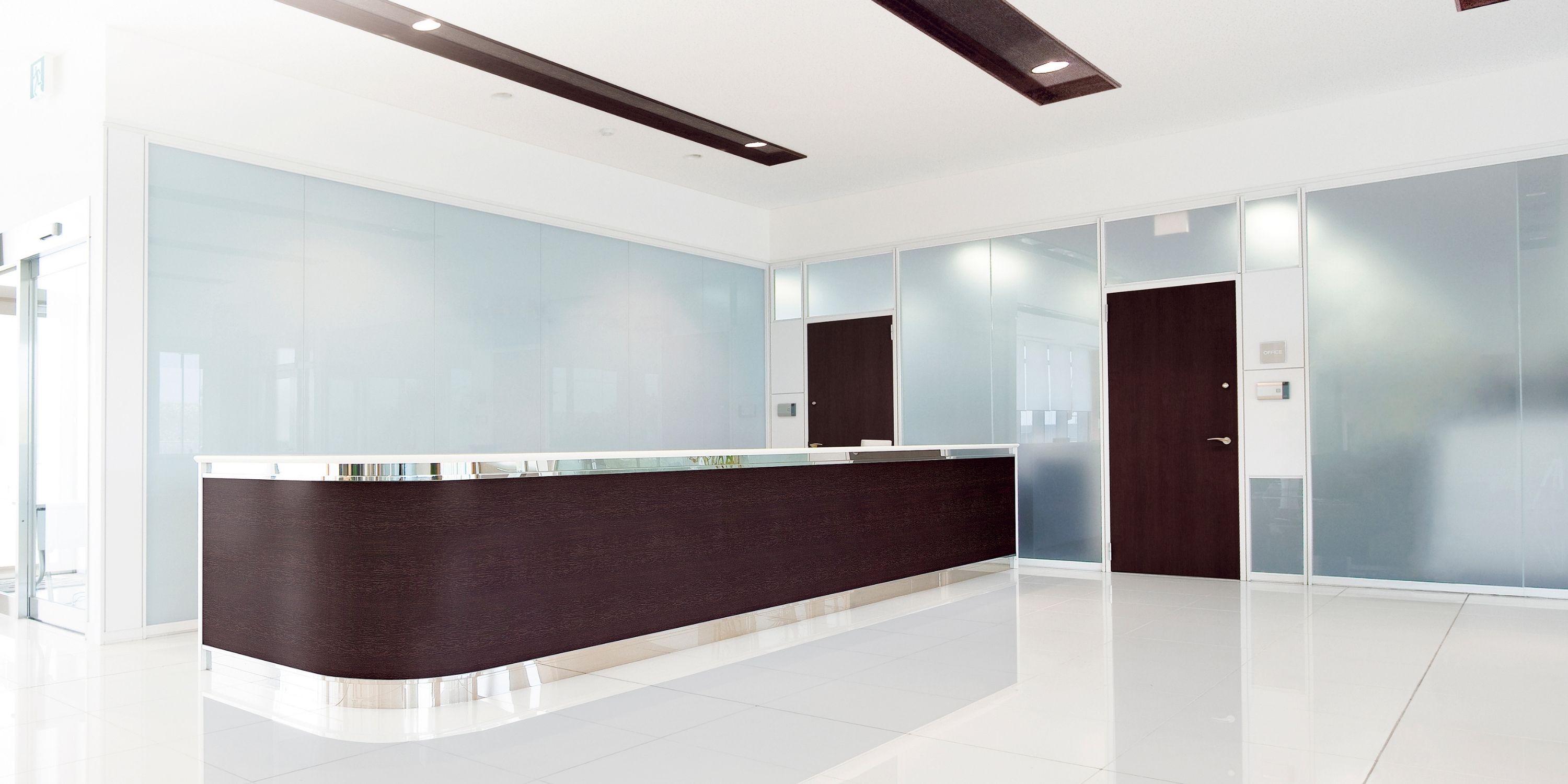 A modern office interior featuring a sleek reception desk and transparent glass walls, creating an open atmosphere.
