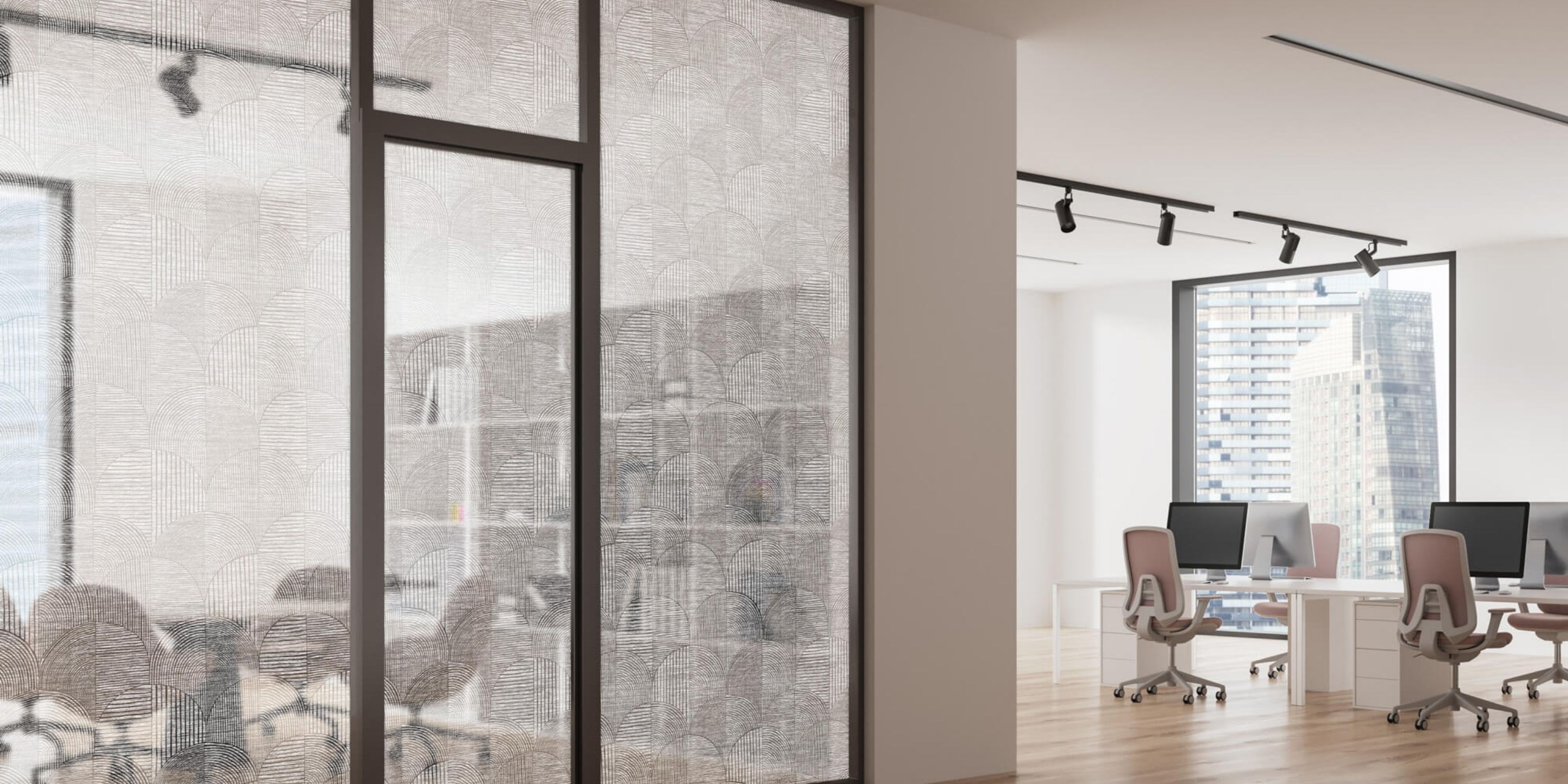 Modern office space with glass partitions, textured patterns, and track lighting. Desks with computers and chairs are visible. Bright, professional atmosphere.