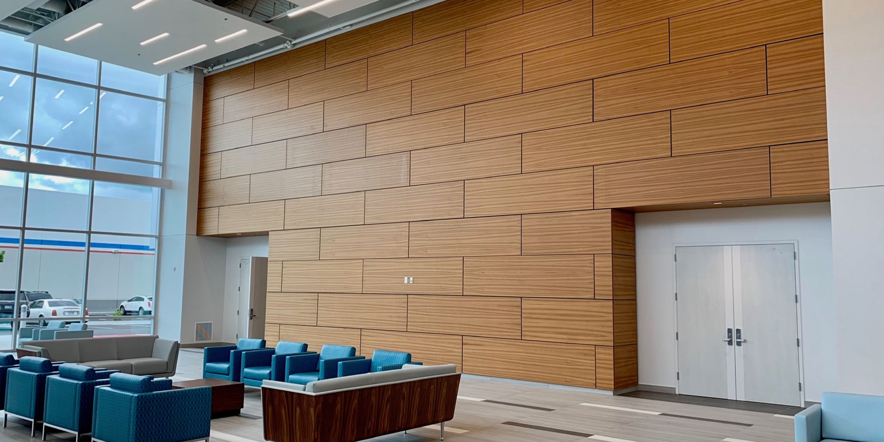 Large lobby interior showcasing wooden paneling and several blue chairs for guests.