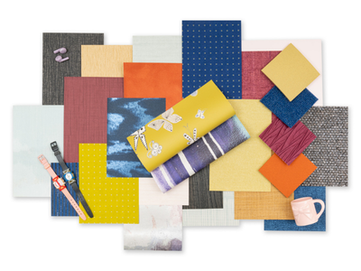 A vibrant collage of multicolored wallcoveringswatches with various textures arranged in layers. Includes a yellow fabric roll, two watches, and a pink mug.