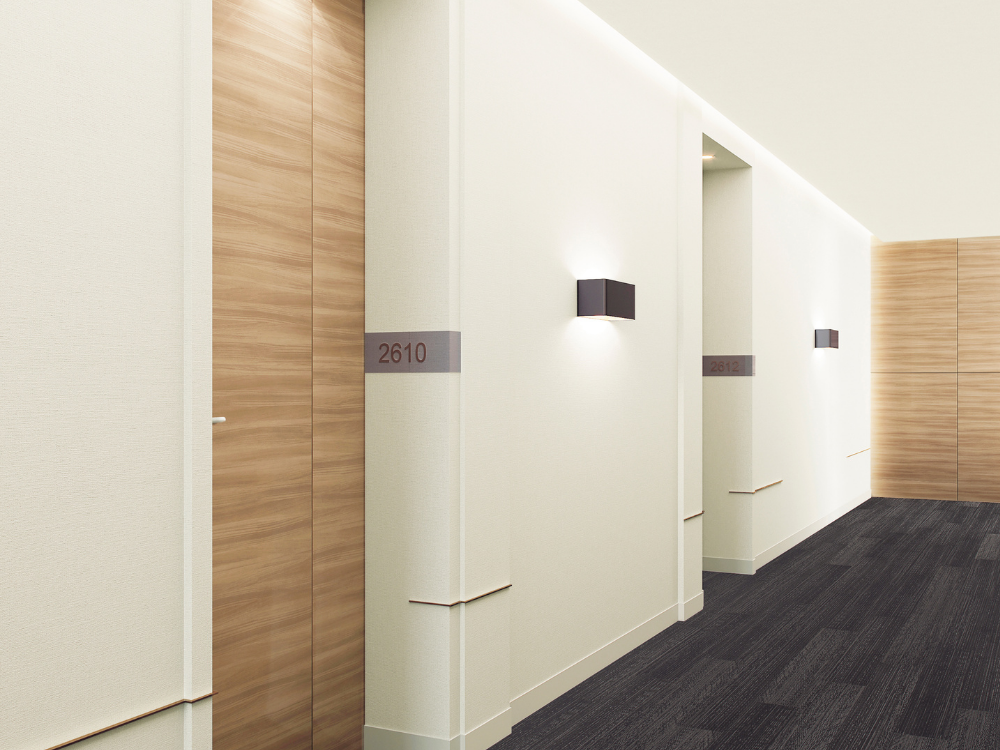 HERITAGE-WOOD-II-(2).png Modern hotel corridor with light wood-paneled doors and bright white walls. Room numbers, including 2610, are labeled neatly. Soft wall lights create a calm ambiance.