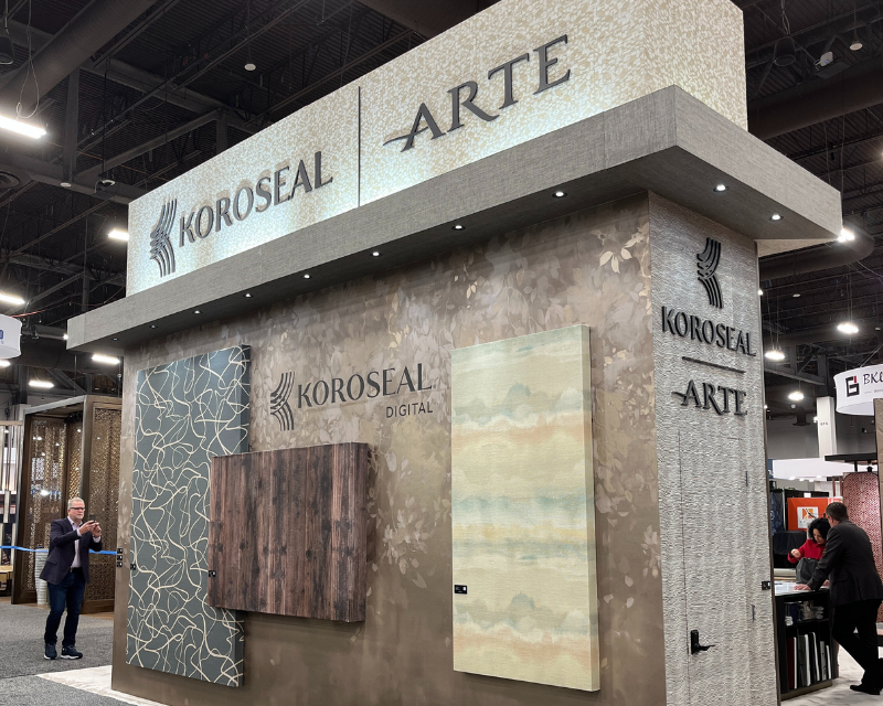 Trade show booth for Koroseal and Arte showcasing textured wall panels with intricate designs. Modern lighting highlights the elegant display.