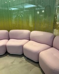 A pink couch positioned against a vibrant green wall, creating a striking color contrast in the room.