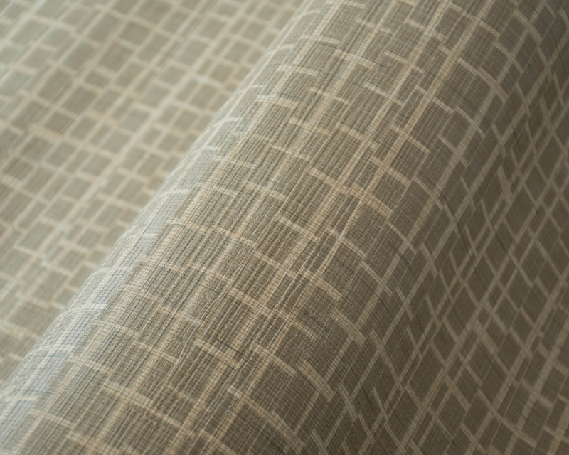 Close-up of fabric with a beige geometric grid pattern, creating a textured appearance. The fabric is draped, suggesting elegance and sophistication.